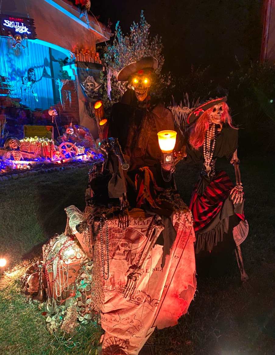 Two skeleton pirates with glowing eyes guard a lantern-lit treasure chest